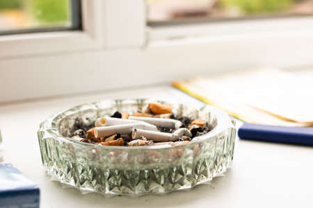 Glass ashtray with cigarette butts in sunlight close upの写真素材