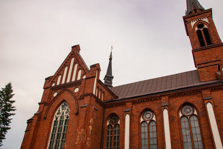 Old catholic church made of red brick on gray sky backgroundの写真素材