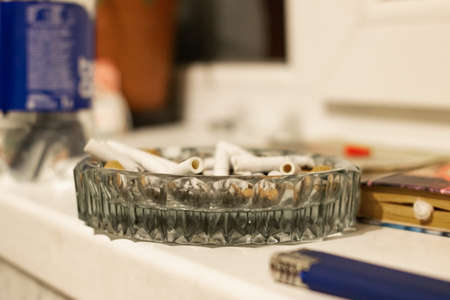 Glass ashtray with cigarette butts in sunlight close upの写真素材