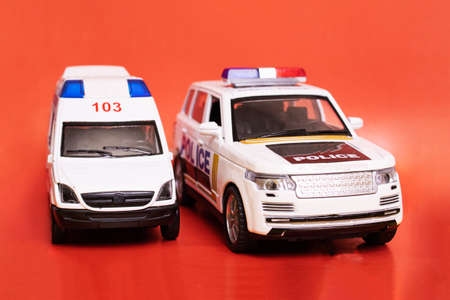 Toy ambulances and police cars on red background closeupの写真素材