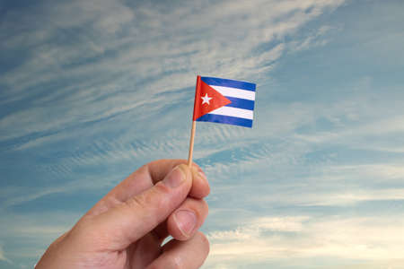 Small Cuba flag in hand on blue sky background close upの写真素材