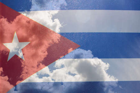 Cuba flag in hand on blue sky with clouds close upの写真素材