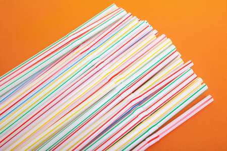 Heap of plastic straws for drink on orange backgroundの写真素材