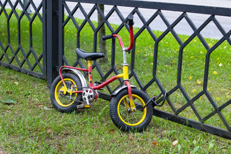 Multi-colored children's bike strapped to the fence close upの写真素材