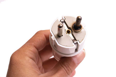 Burnt electrical plug in hand isolated on white background close upの写真素材