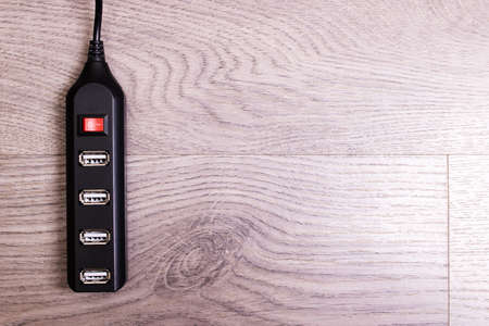 Black USB hub on a wooden background close up, copy spaceの写真素材