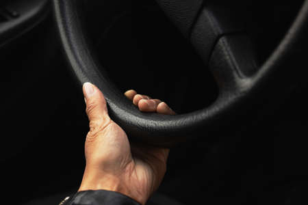 Hand on the steering wheel of a car close upの写真素材