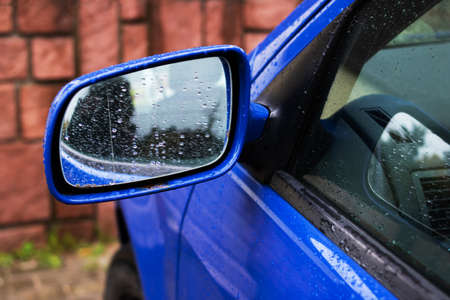Side mirror on a blue car with rain drops close upの写真素材