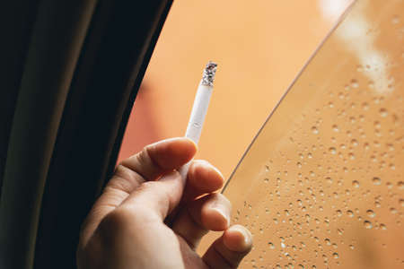 Cigarette in hand by the car window close upの写真素材