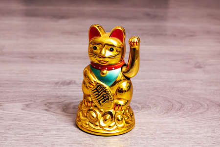 Statuette of maneki neko on wooden floor close upの写真素材