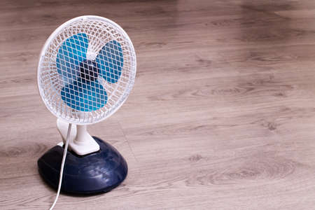 Small fan on the wooden floor close up, copy space
