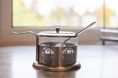 Metal sugar bowl on the table against the background of the windowの写真素材