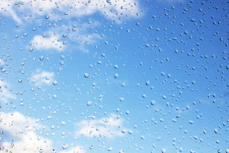 Drops on glass against a bright blue sky, background or textureの写真素材