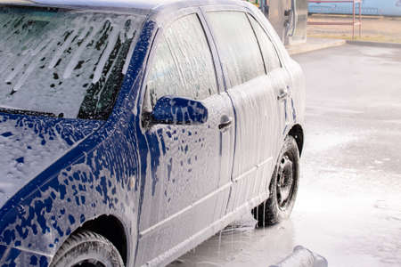 Blue car in foam at a car washの写真素材