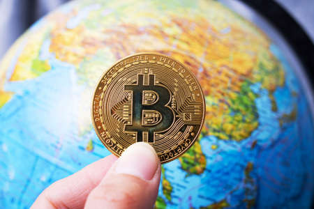 Bitcoin on the background of a globe with a mapの写真素材