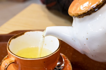 Tea is pouring from the teapot into the cup close upの写真素材