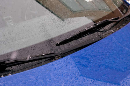 Wipers on the glass of a blue car in the rainの写真素材