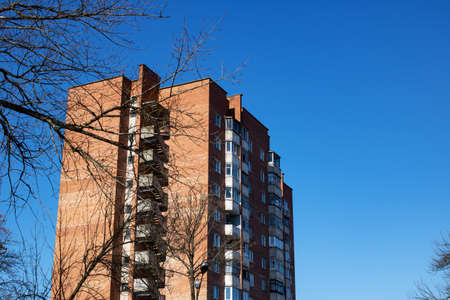 Old high house and bare branches on blue sky background