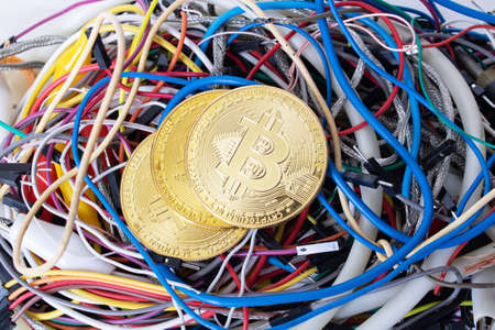 Bitcoins on the background of colored computer wires close up