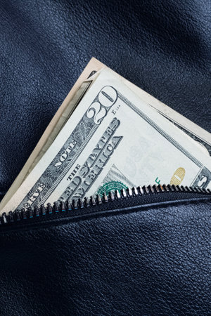 Dollars in the pocket of a black leather bag close upの写真素材