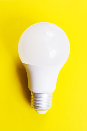 Light bulb on bright yellow background close up