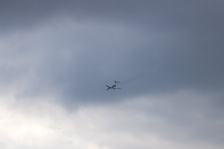 The plane flies high in the gray sky close up