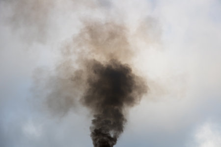 Black smoke from the chimney of the plant on the background of the skyの写真素材