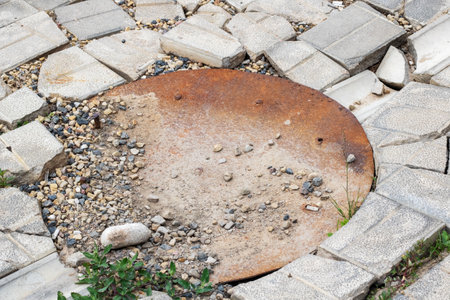 Old rusty manhole in paving slabs close up