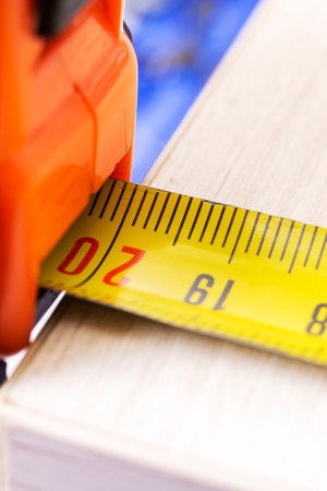 Measuring a wooden board with a construction tape close upの写真素材
