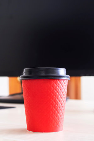 Red plastic coffee cup on the desktop close upの写真素材