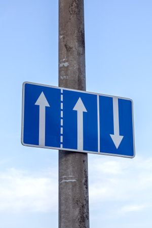 Road sign with arrows on blue sky background close upの写真素材