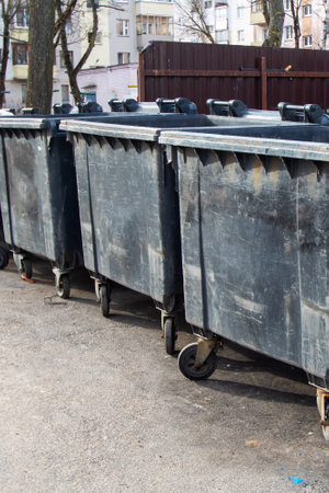 Black big garbage cans on asphalt close up