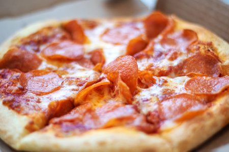 A pepperoni pizza, a staple food in fast food cuisine, rests in a cardboard box. This baked goods dish is a classic recipe of Californiastyle pizzaの写真素材