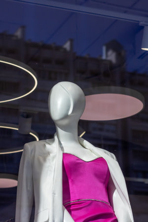 A mannequin is dressed in a pink dress and a white jacket, showing a blend of fashion design elements. The colors used are pink and whiteの写真素材