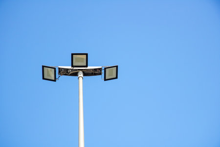 A streetlight towers high, silhouetted against the backdrop of a serene, cloudless sky, casting its...