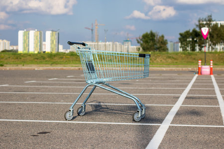 There is an empty shopping cart abandoned in a parking lot areaの写真素材