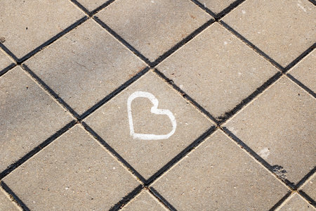 A white heart design has been drawn onto a brick sidewalk surface