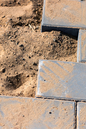 A sturdy and aesthetically pleasing brick walkway is currently being constructed on a soft sandy...
