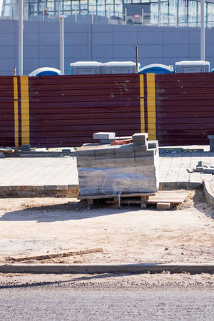 A busy construction site featuring a massive building prominently positioned in the background,...