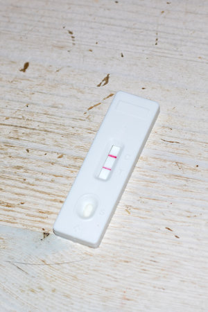 A negative pregnancy test is shown lying on a wooden surface, possibly symbolizing a lack of desired...