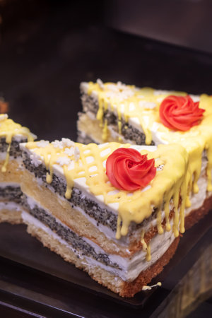 A delightful slice of cake beautifully adorned with vibrant yellow frosting as well as a charming red rose artfully placed on topの写真素材