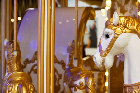 A beautifully designed merrygoround featuring exquisite gold and white horses that add a touch of elegance and charm to the rideの写真素材