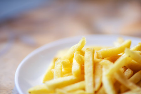 A delightful and crispy pile of goldenbrown French fries is beautifully arranged on a pristine white plate, ready to be enjoyedの写真素材