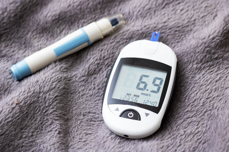 A glucose meter provides a reading alongside an insulin injection pen, all displayed over a soft backgroundの写真素材