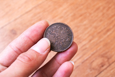 A person is skillfully holding a shiny coin delicately between their fingers, showing the intriguing...