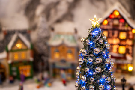 A beautifully decorated Christmas tree, complete with a bright star on top, stands proudly in a serene, snowy village settingの写真素材