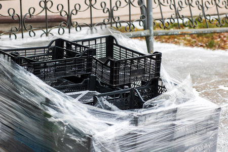 A collection of plastic crates is now completely wrapped in a layer of plastic material, providing...