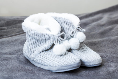 A cozy pair of soft gray slippers that feature charming white pom poms, perfect for keeping little feet warm and stylishの写真素材