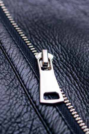 A closeup view of a sleek black leather jacket that showcases luxurious fur trim along with intricate zipper detailsの写真素材