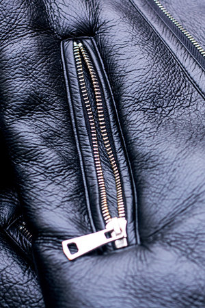 A closeup view of a sleek black leather jacket that showcases luxurious fur trim along with...